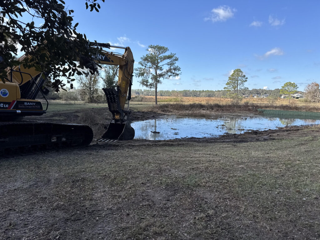 Excavator dredging sediment from a pond